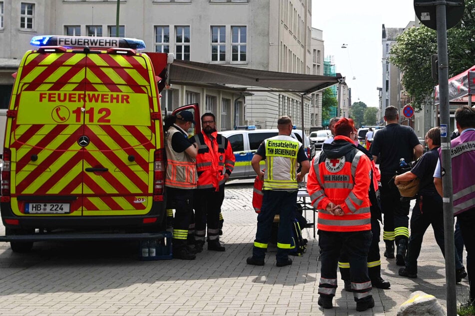 Rettungskräfte stehen vor dem Gymnasium in Bremerhaven. Am Donnerstag fielen dort Schüsse, eine Frau wurde lebensgefährlich verletzt. Der Täter wurde verhaftet.