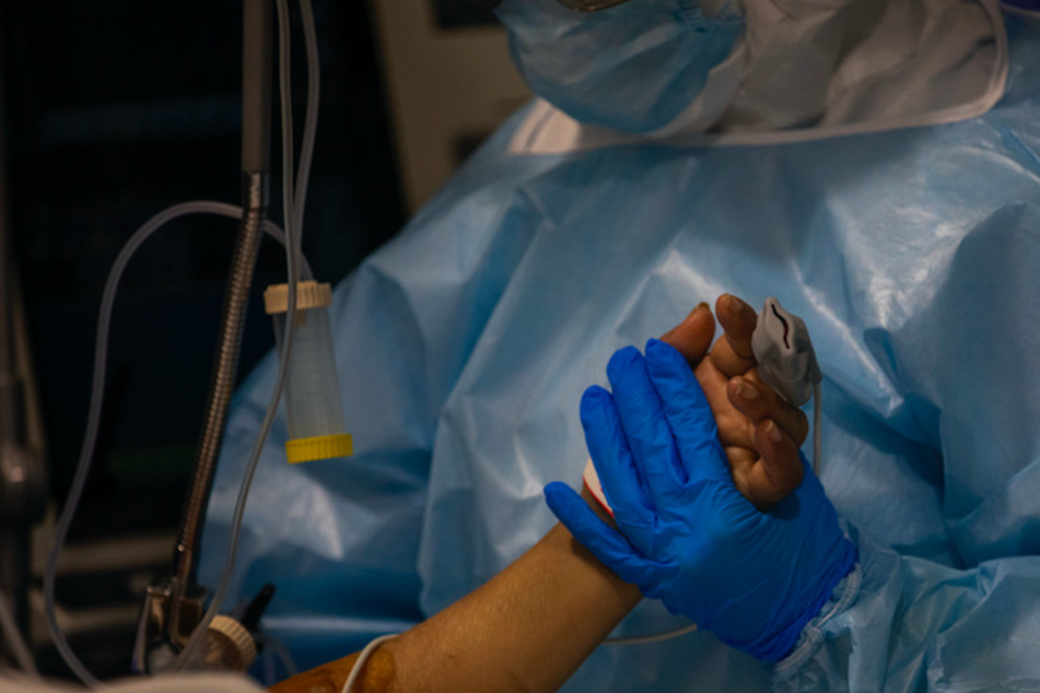 Ein Arzt hält die Hand eines Covid-19-Patienten. (Symbolbild)