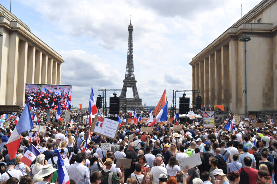 24.07.2021, Frankreich, Paris: Demonstranten nehmen auf der «Droits de l'homme»-Esplanade am Trocadero-Platz an einem Protest gegen die Impfpflicht für bestimmte Arbeitszweige und den von der Regierung geforderten obligatorischen Impfass teil. Foto: Alain Jocard/AFP/dpa +++ dpa-Bildfunk +++