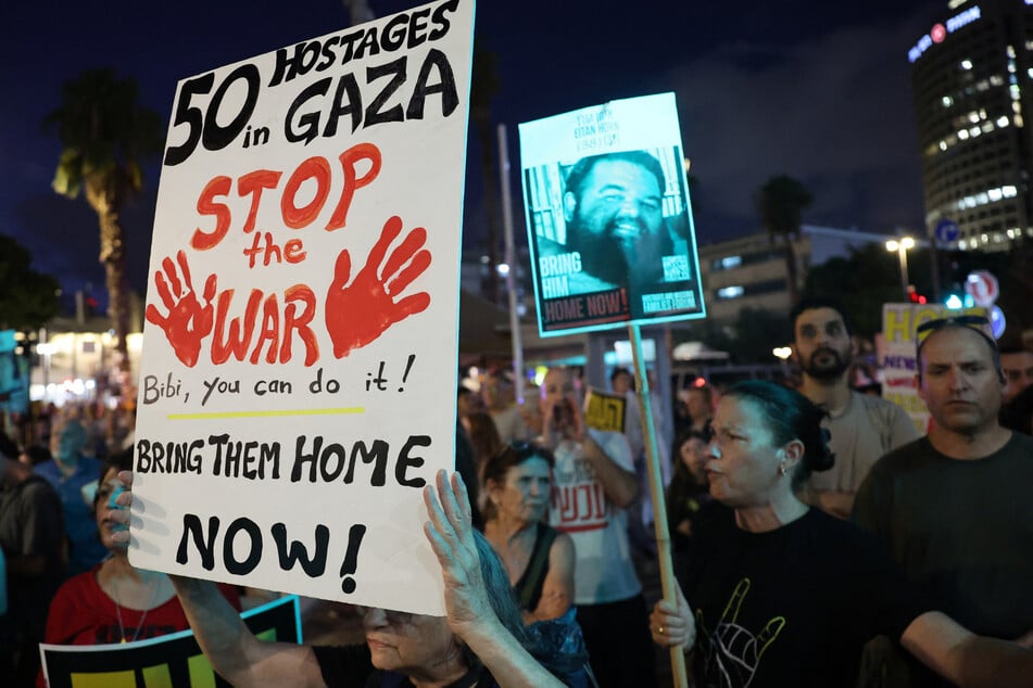 Demonstrators raise signs during an anti-government protest calling for the release of Israeli hostages in Gaza, outside the Israeli Defense Ministry headquarters in Tel Aviv on August 6, 2025.