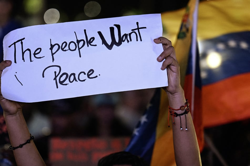 A supporter of Venezuela's President Nicolas Maduro holds a sign during a rally demanding peace in Caracas on December 15, 2025.