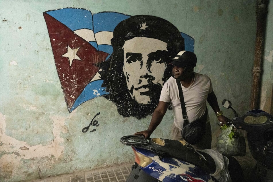 A man parks a motorbike in front of a mural depicting Argentine-born Cuban revolutionary Ernesto "Che" Guevara after a blackout in Havana on March 4, 2026.