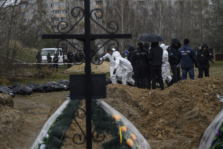 Personen in Schutzkleidung tragen die Leichen getöteter Zivilisten in Butscha am Stadtrand von Kiew.