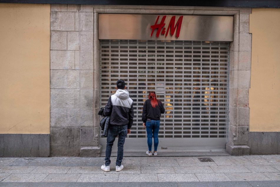 Spanien, Barcelona: Passanten stehen vor einer geschlossenen H&M-Filiale im Einkaufsviertel Portal del l'Angel.