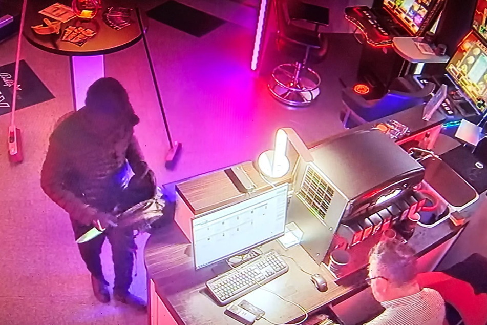 Das Überwachungsvideo zeigt den Täter mit Messer. Rechts im Bild: Der Spielhallen-Mitarbeiter.