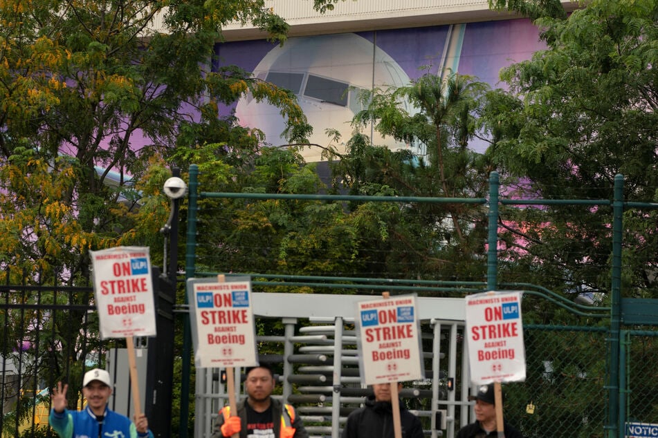 The image of a Boeing 737 jetliner is seen behind Boeing factory workers and supporters as they gather on a picket line in Renton, Washington.