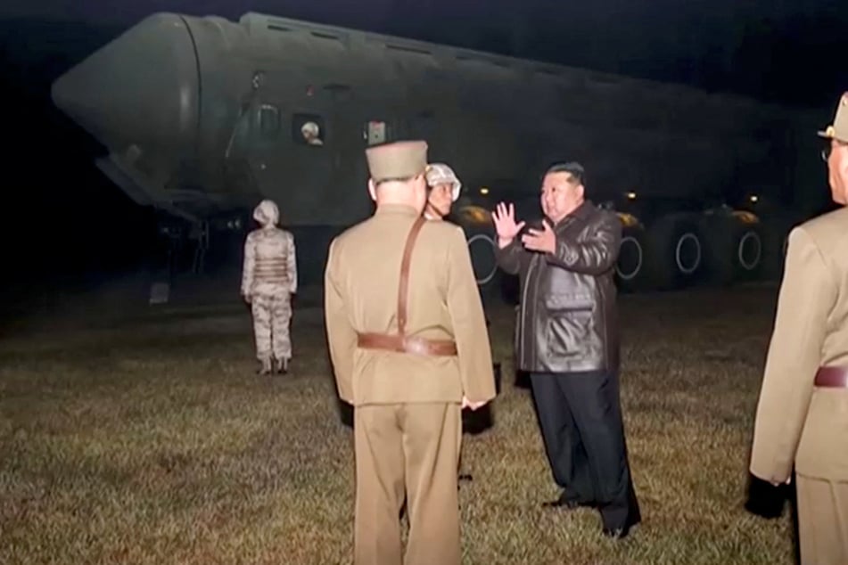 North Korean leader Kim Jong Un and military officials stand next to what they say is a mobile missile launcher vehicle at an undisclosed location.