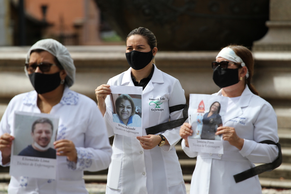 Members of the Amazon Regional Council of Nurses (COREN-AM) wearing black masks as a symbol of mourning show photos of colleagues who died in the fight against the coronavirus on International Nursing Day.