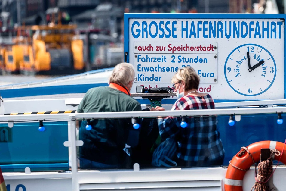 Passagiere sitzen auf dem Außendeck einer Barkasse.