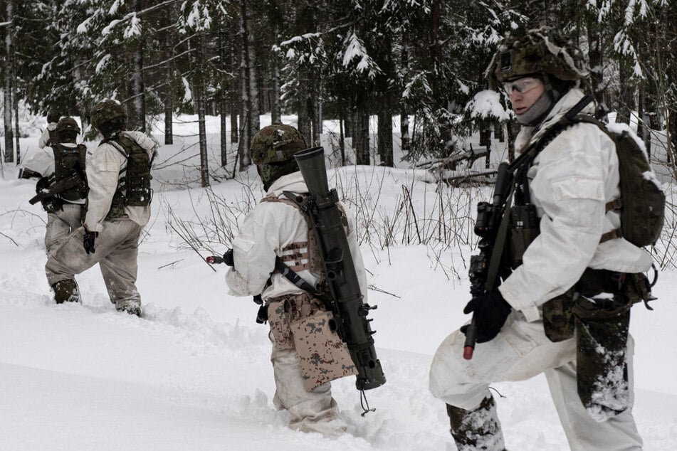 Soldaten der Estnischen Armee bei einer NATO-Übung in einem verschneiten Wald.