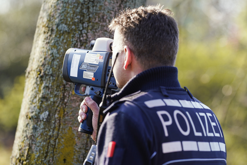 Ein Polizist kontrolliert mit einem Lasergerät an der Bundesstraße 36 in Mannheim die Geschwindigkeit von Fahrzeugen.