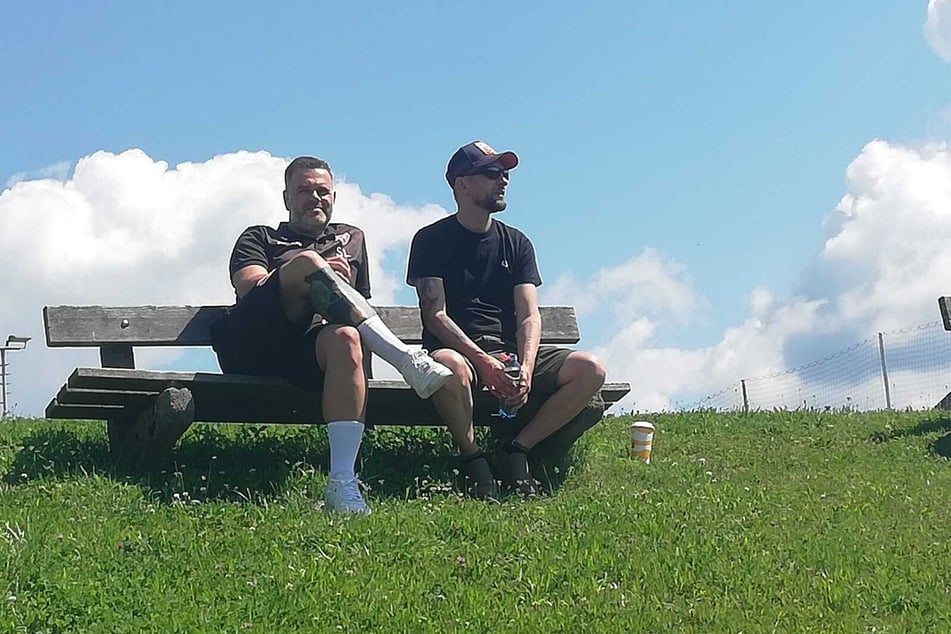 Präsident Sebastian Lemke (l.) hat es sich nach langer Autofahrt auf einer Bank in der Sonne bequem gemacht.