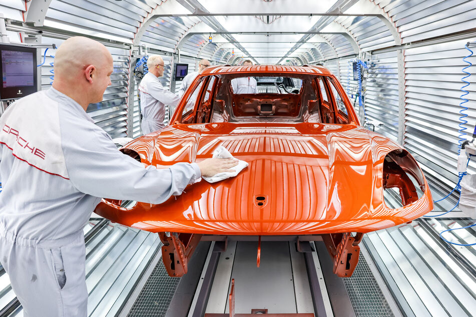 Mitarbeiter der Lackiererei arbeiten in der Qualitätskontrolle an einem Porsche Macan im Werk Leipzig.