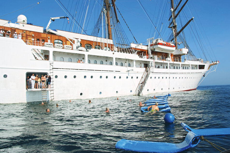 Passagiere der Sea Cloud Cruises schwimmen neben dem Kreuzfahrt-Schiff. (Archivbild)