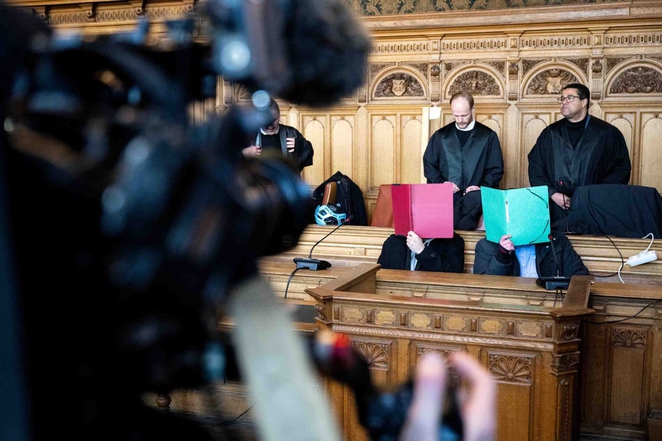 Zwei der drei Angeklagten sitzen in Bremen vor Prozessbeginn im Gerichtssaal. Ihnen wird vorgeworfen, im April 2020 einen Mann getötet zu haben.