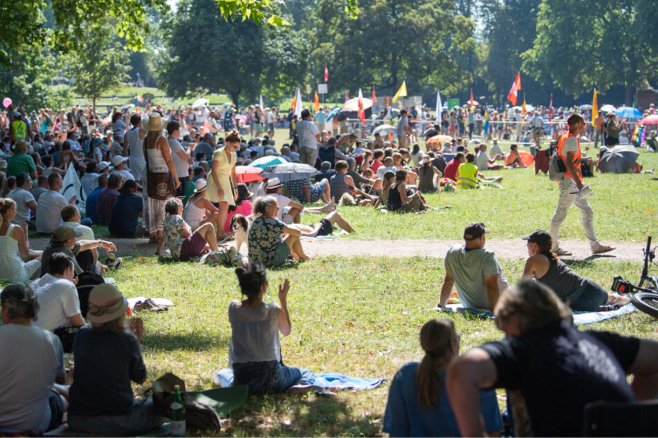 Teilnehmer sitzen während einer Kundgebung der Initiative "Querdenken 711" im unteren Schlossgarten in Stuttgart.