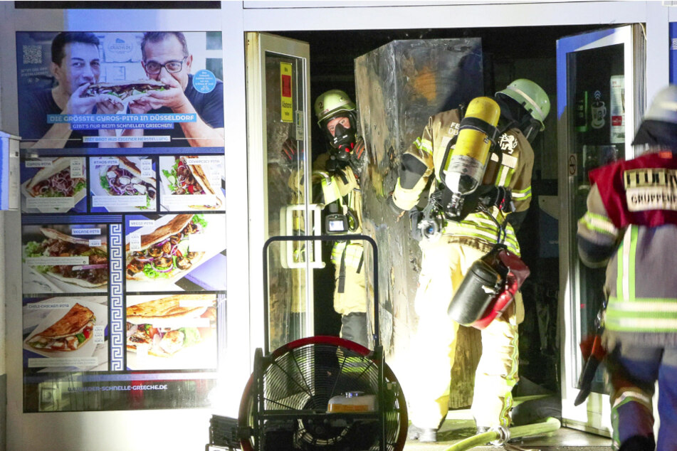 Einsatzkräfte der Feuerwehr tragen einen völlig abgefackelten Spind nach draußen - war er Auslöser für den heftigen Brand?