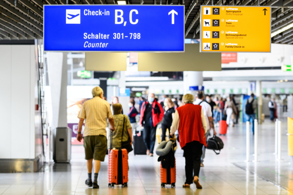 Reisende gehen am Flughafen mit Gepäck durch die Abflughalle im Terminal 1.