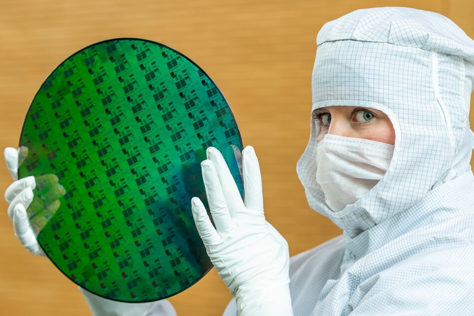 Eine Auszubildende präsentiert einen 300-Millimeter-Wafer in der Chipfabrik von Globalfoundries in Dresden.