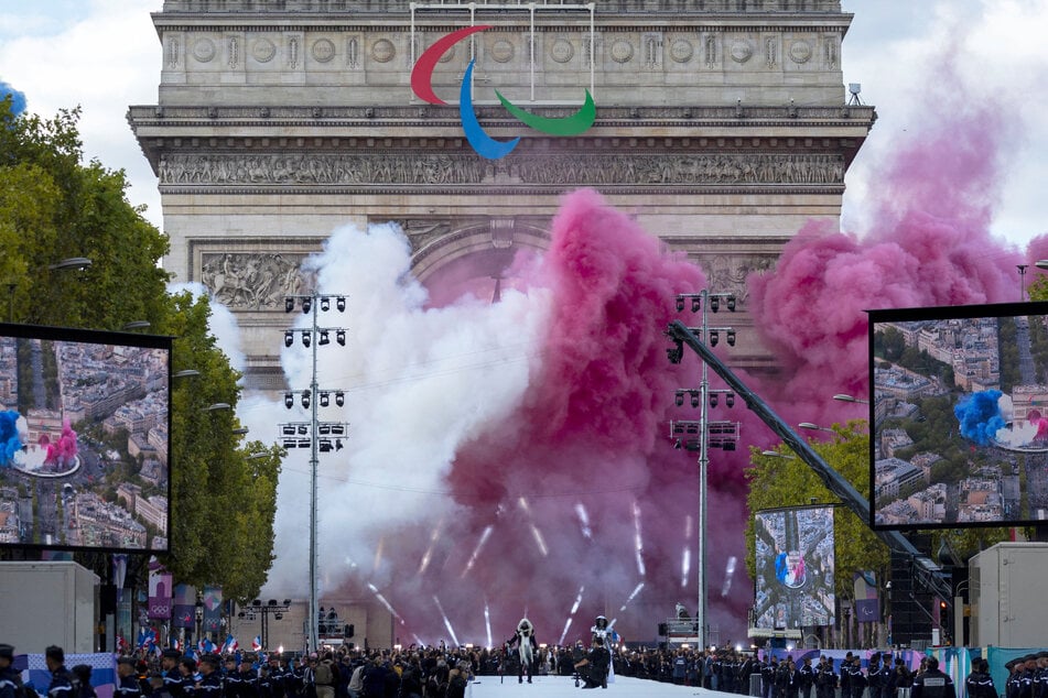 Smoke with the French national colors rises from the Arc de Triomphe monument as French Olympic and Paralympic athletes take part in a parade on the Champs Elysees avenue in Paris.