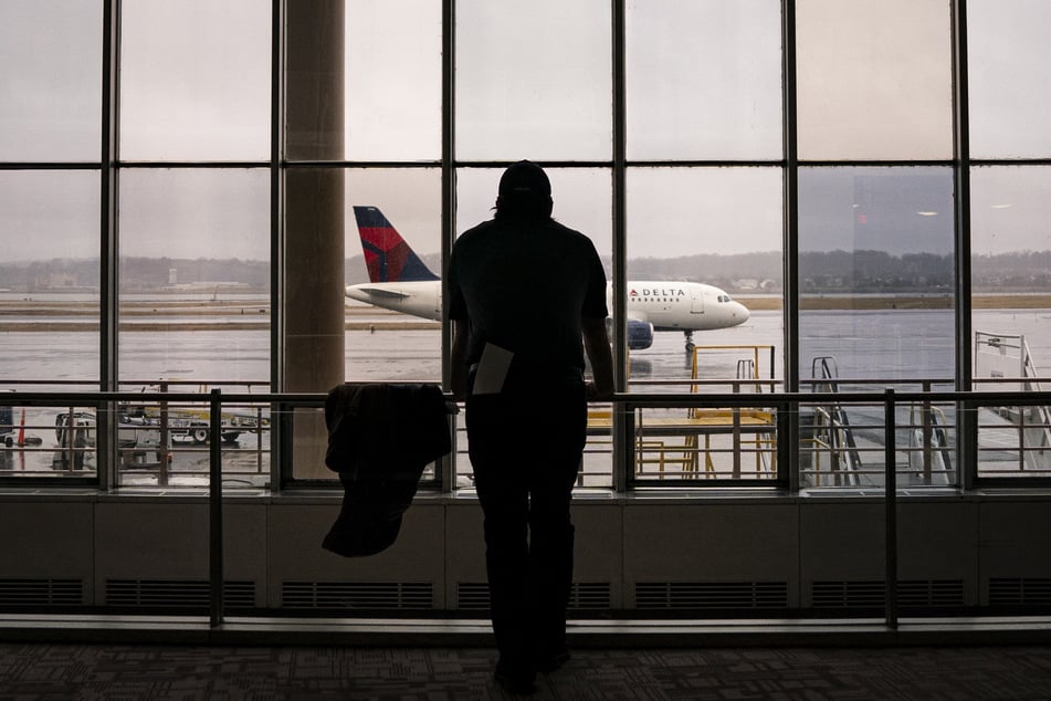 A worker looks out at a passing Delta Airlines plane in Terminal 1 at Ronald Reagan National Airport, on February 6, 2025 in Arlington, Virginia.