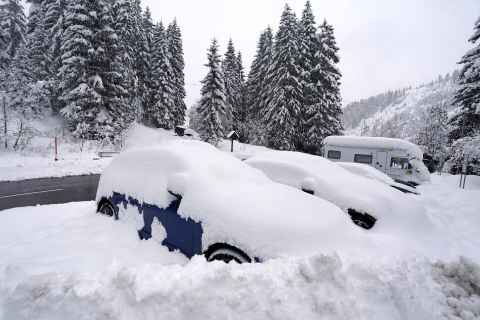 Eingeschneite Autos stehen am Riedbergpass bei Sonthofen (Bayern) in winterlicher Landschaft.