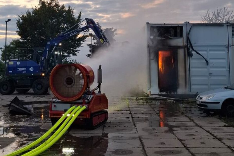 Ein ferngesteuertes Löschunterstützungsfahrzeug vor dem brennenden Batteriespeicher.
