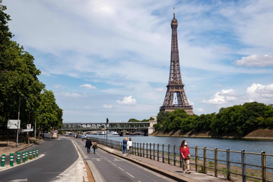 Frankreich, Paris: Menschen spazieren an der Seine neben dem Eiffelturm.