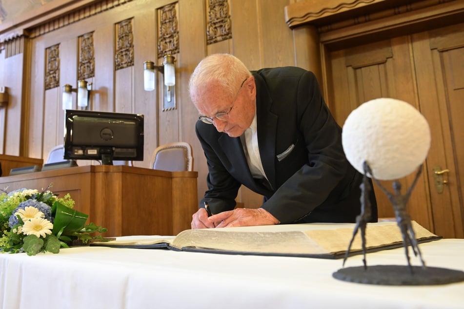 Hartwig Albiro (89) trägt sich in das Goldene Buch der Stadt ein. Die Bronze-Skulptur "Gemeinsam sind wir stark" gab es für die AG dazu.