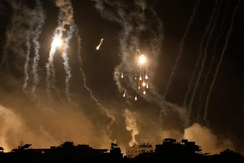 Rauch steigt während eines israelischen Luftangriffs im Gazastreifen auf und Leuchtraketen erhellen den Himmel.