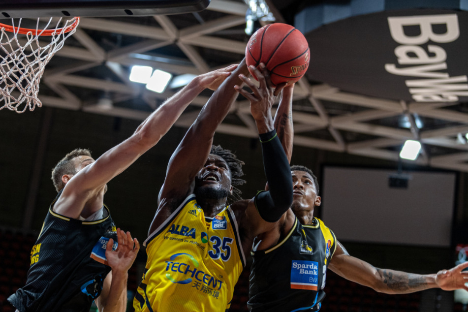Berlins Landry Nnoko (M) und Ludwigsburgs Jonas Wohlfarth-Bottermann gehen zum Ball.