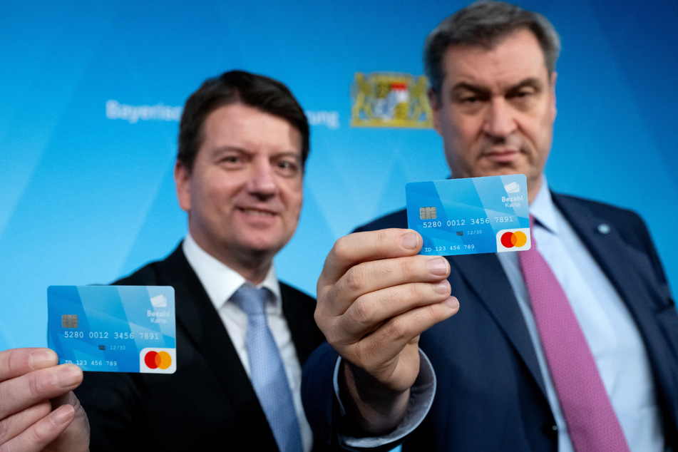 Sandro Kirchner (48, CSU, l.), Innenstaatssekretär von Bayern, und Markus Söder (57, CSU), Ministerpräsident von Bayern, halten die bayerische Bezahlkarte für Asylbewerber in den Händen.