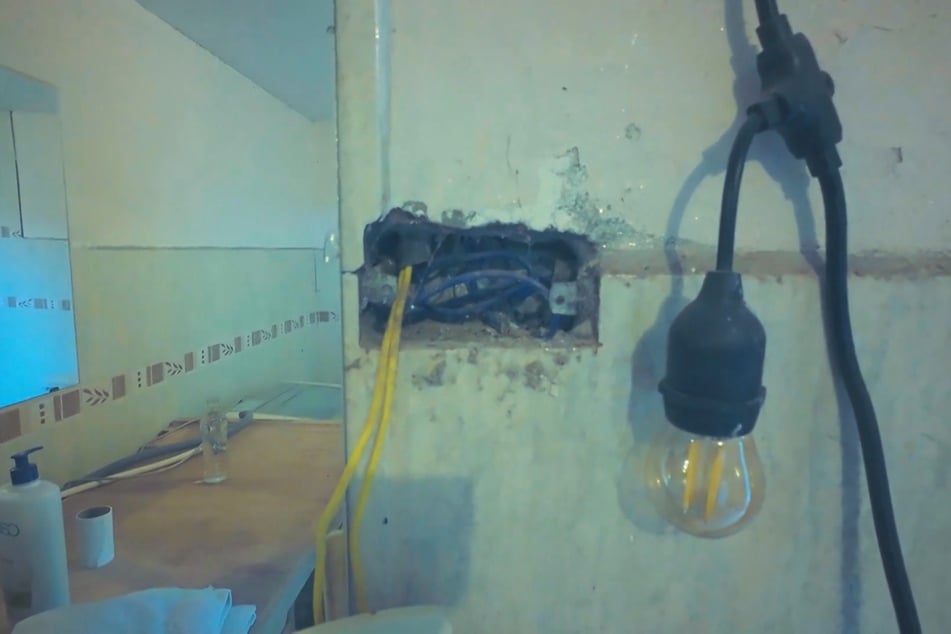 Äußerst provisorisch ragen Kabel aus einem Loch in der Fliesenwand.