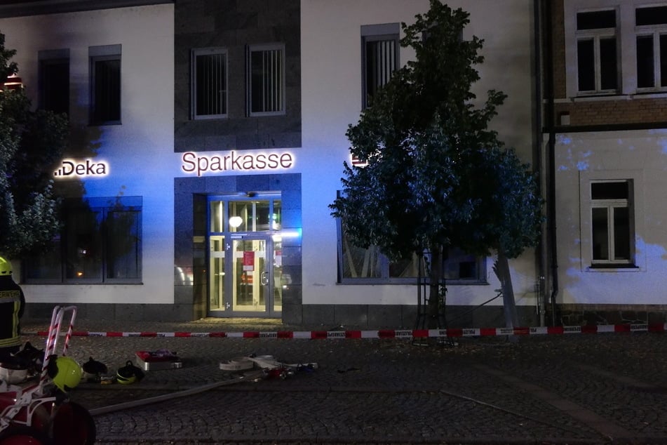 Feuerwehrleute sichern kurz nach der Explosion das Sparkassen-Gebäude.