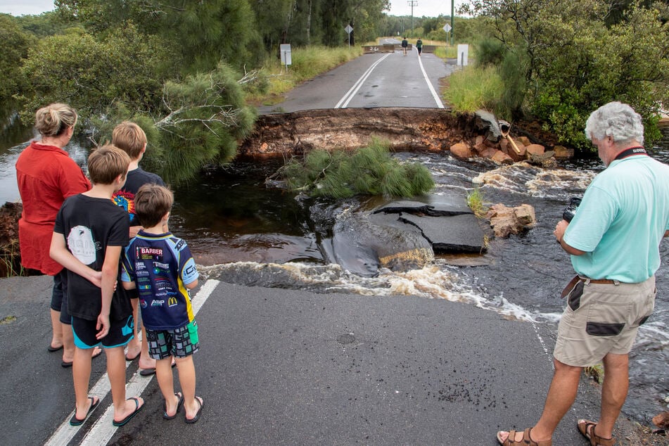 Port Stephens: Menschen stehen an einem unterspülten Straßenabschnitt 200 Kilometer nördlich von Sydney.