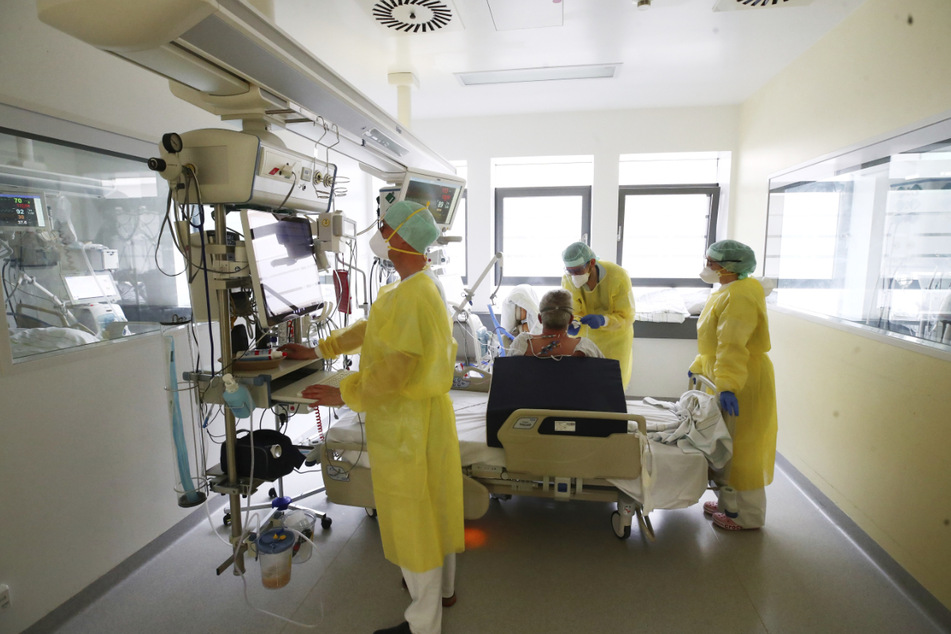 Ärzte und Pfleger untersuchen einen Patienten auf einer Covid-19-Intensivstation in Thüringen. Im Freistaat bleibt die Zahl der täglichen Neuinfektionen auf hohem Niveau.