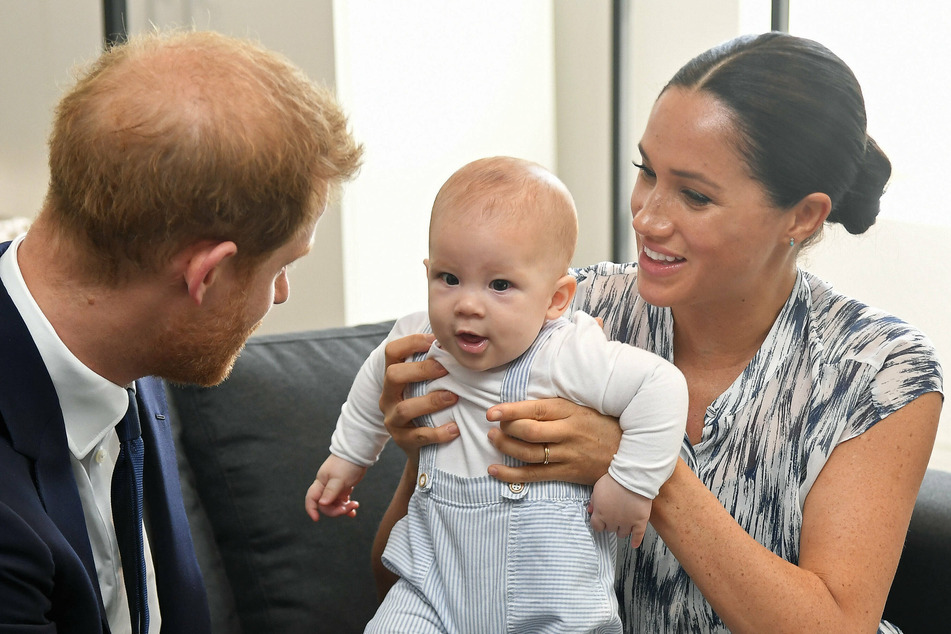 Prince Harry (36) and his wife Meghan (39) hold up their son Archie (1).