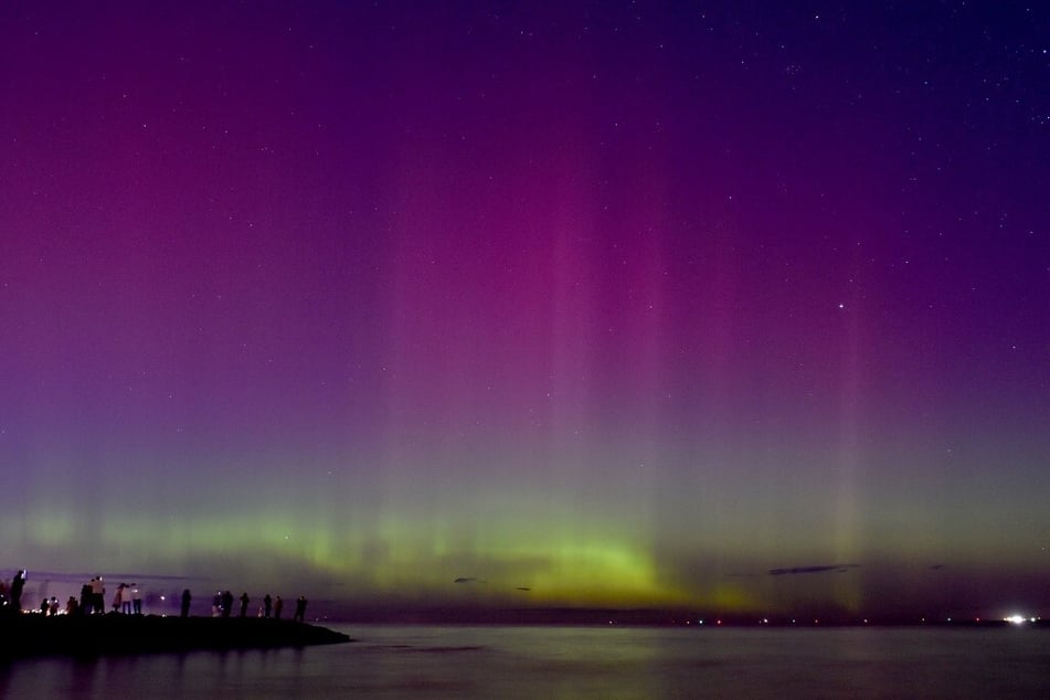 People watch the aurora australis or southern lights caused by a solar storm at Port Phillip Bay in Melbourne, Australia.
