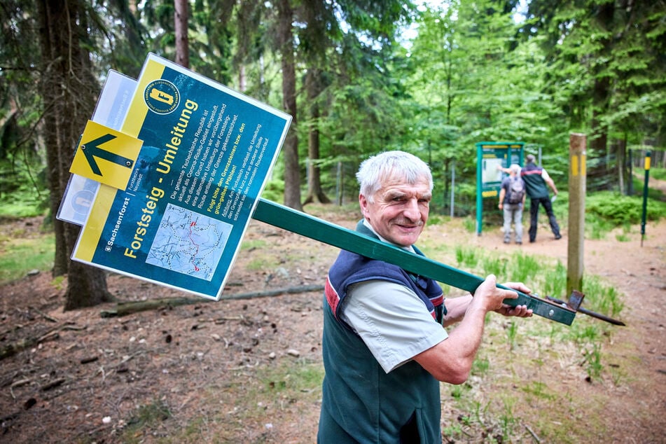 Cunnersdorf bei Königstein: Forststeig-Ranger Wolfram Claus trägt ein abgebautes Hinweisschild. Der nach Tschechien führende Wanderweg Forststeig ist nach Aufhebung der Einschränkungen während der Corona-Pandemie wieder durchgängig offen.