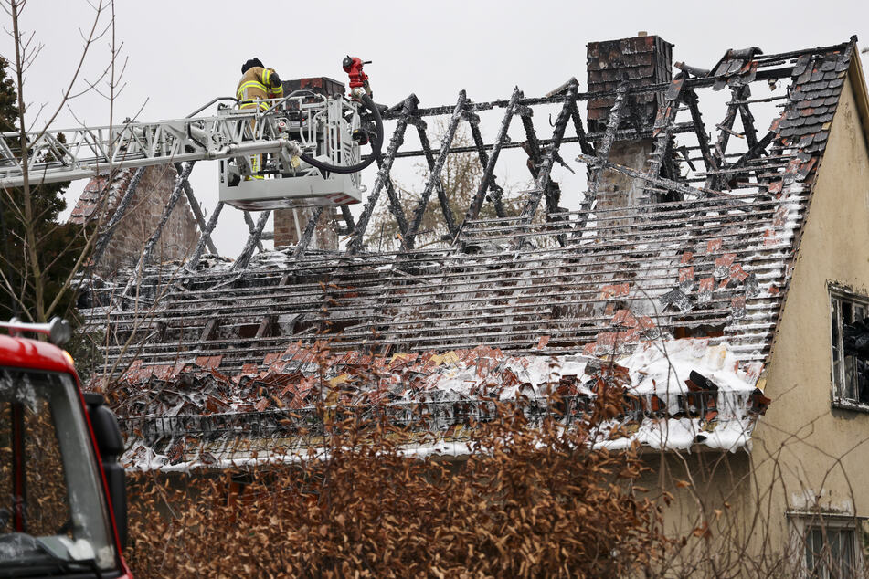 Von einer Drehleiter aus sucht ein Feuerwehrmann nach Glutnestern nach einem Brand im Dachstuhl des leer stehenden Einfamilienhauses.