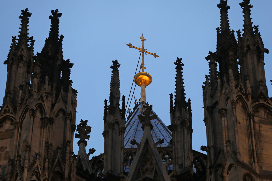 Ein goldenes Kreuz auf dem Kölner Dom: Nach Monaten der öffentlichen Kritik hat die katholische Kirche einer Umfrage zufolge massiv an Glaubwürdigkeit eingebüßt.