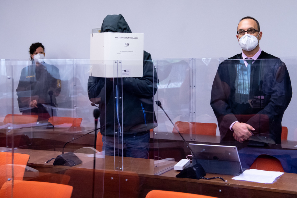 Der wegen schweren sexuellen Missbrauchs angeklagte Mann (M) steht vor Prozessbeginn im Landgericht neben seinem Anwalt Adam Ahmed (r) im Verhandlungssaal.