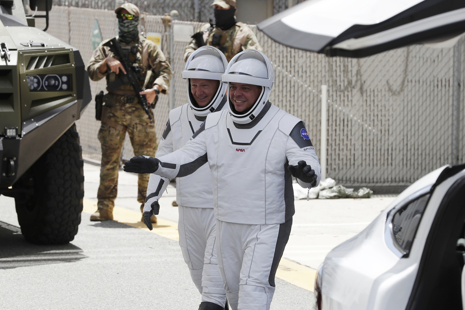 Die NASA-Astronauten Douglas Hurley (l.) und Robert Behnken, lächeln, während sie das Neil Armstrong Operations and Checkout Building auf ihrem Weg zur Startrampe 39A verlassen, an der eine "Falcon 9"-Rakete zum Start bereit steht.