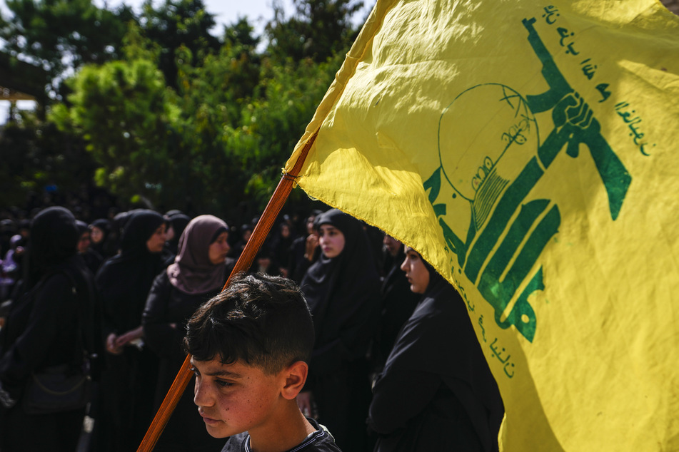 Ein minderjähriger Junge hält im Libanon eine Hisbollah-Fahne in die Höhe.