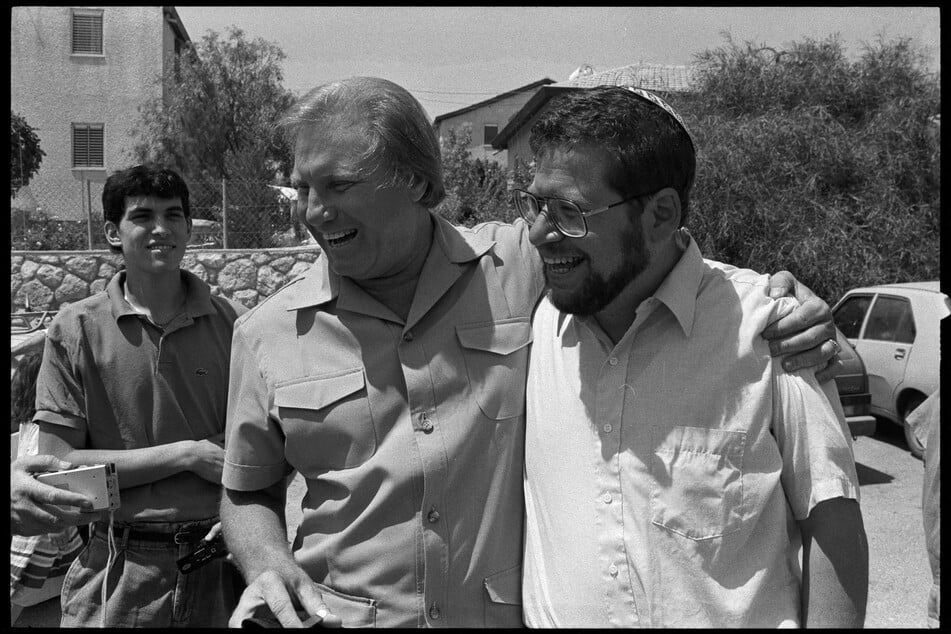 Jimmy Swagart (c.) embraces Bobby Brown (r.), an ultra-nationalist Jewish settler originally from New York, as they both laugh while exchanging remarks about their respective controversies in the illegally occupied West Bank in 1988.