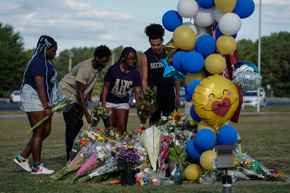 Mourners lay flowers at the site of a makeshift memorial at Apalachee High School the day after a fatal shooting left four dead in Winder, Georgia.