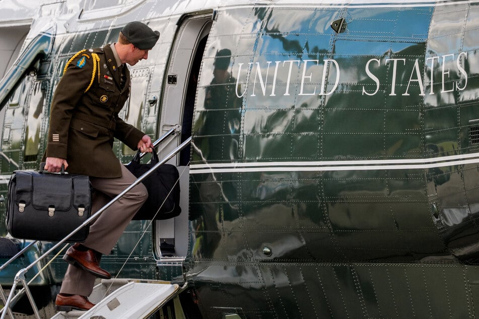A military aide carries the "nuclear football," which contains launch codes for nuclear weapons as he boards Marine One to join President Donald Trump on October 10, 2025.
