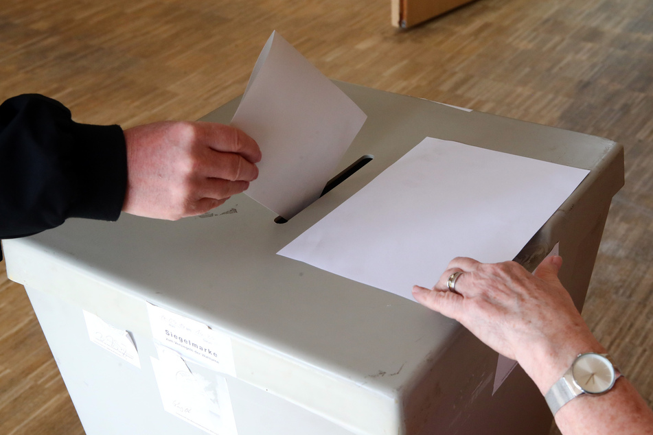 Eine Wählerin wirft ihren Wahlschein in einem Wahllokal in die Wahlurne.