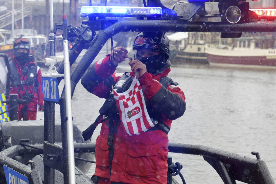 Ein Beamter der Wasserschutzpolizei hisst die Bremen-Fahne an dem neuen Polizeiboot.