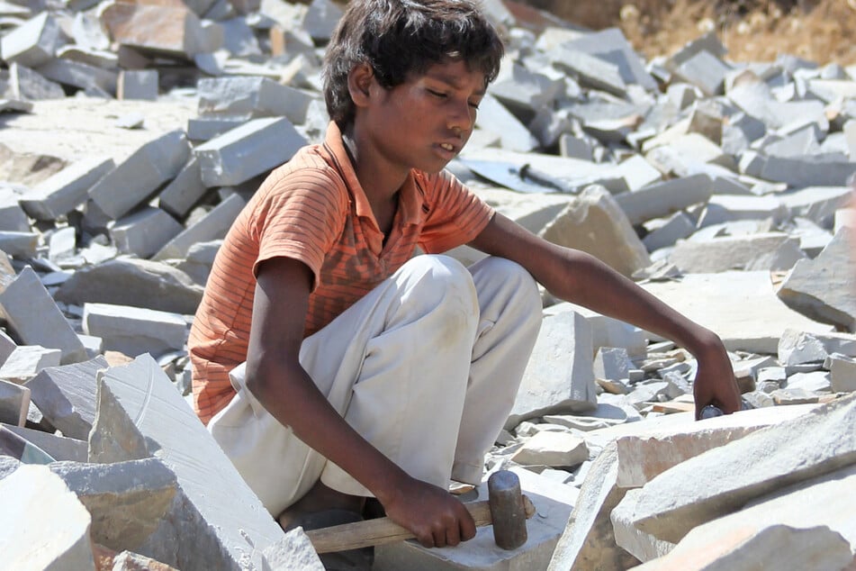 Ein kleiner Junge sitzt in der indischen Provinz Rajasthan mit einem Hammer auf Marmorsteinen. Tausende Kinder hauen in indischen Steinbrüchen Steine für den europäischen Markt.